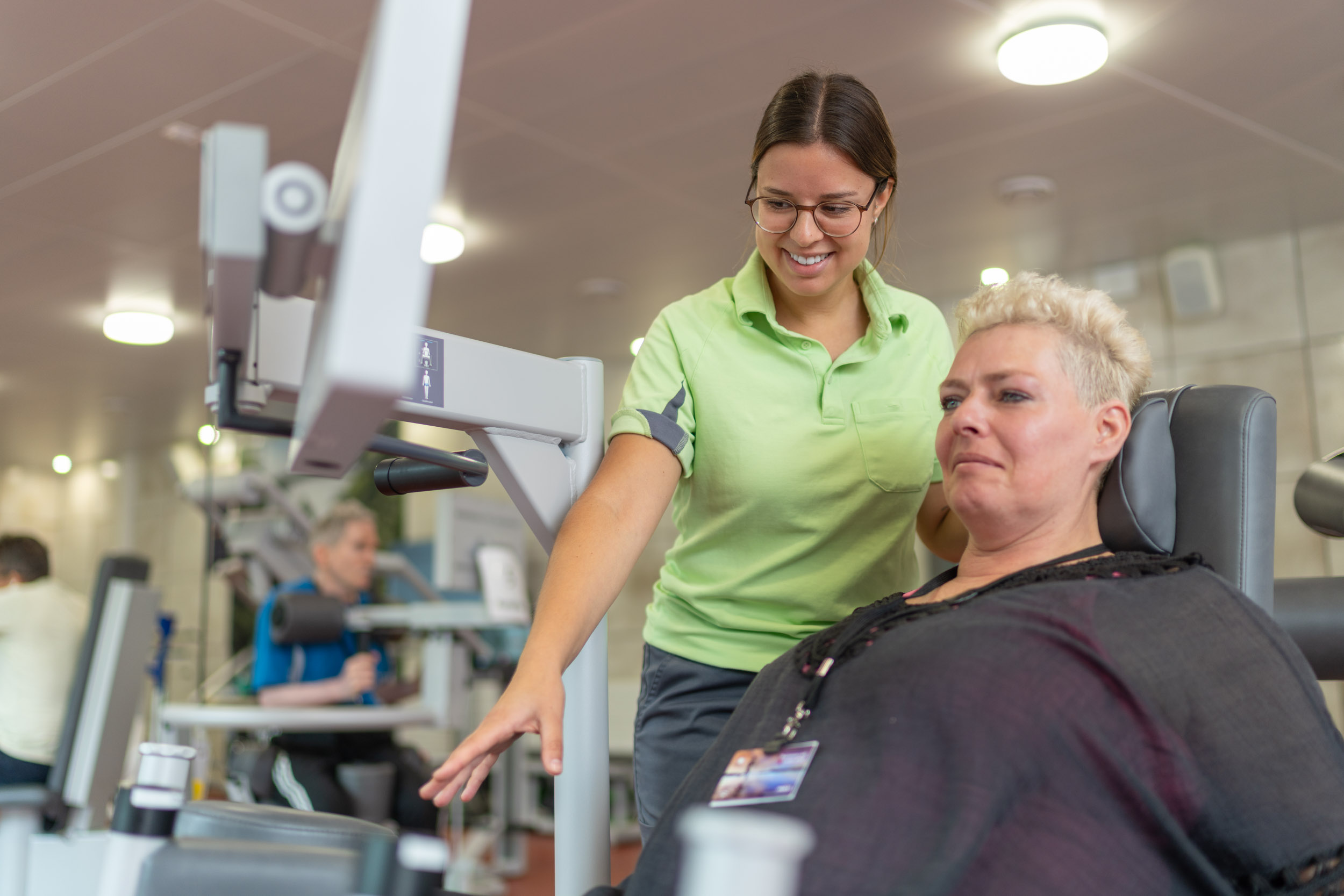 Therapeutin mit Patientin an einem Trainingsgerät