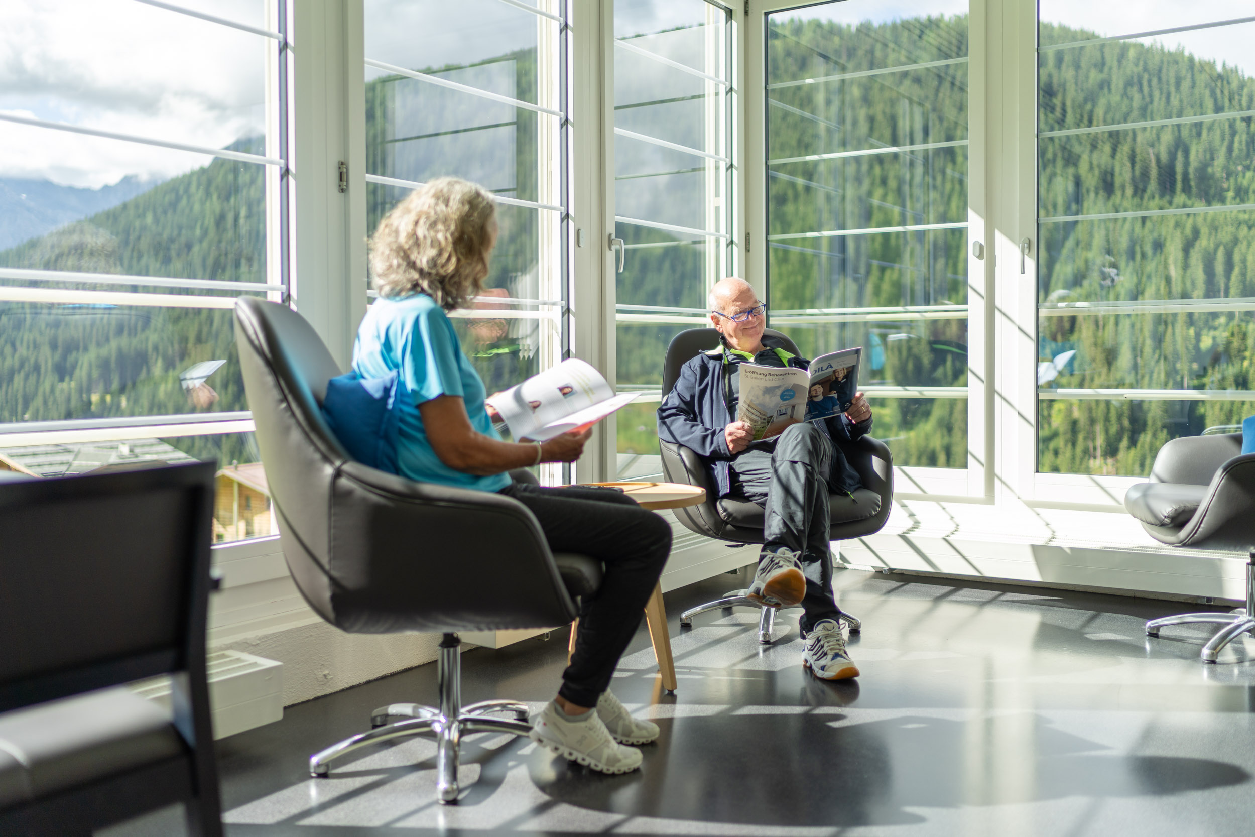 Patientin und Patient sitzen im Wintergarten und lesen