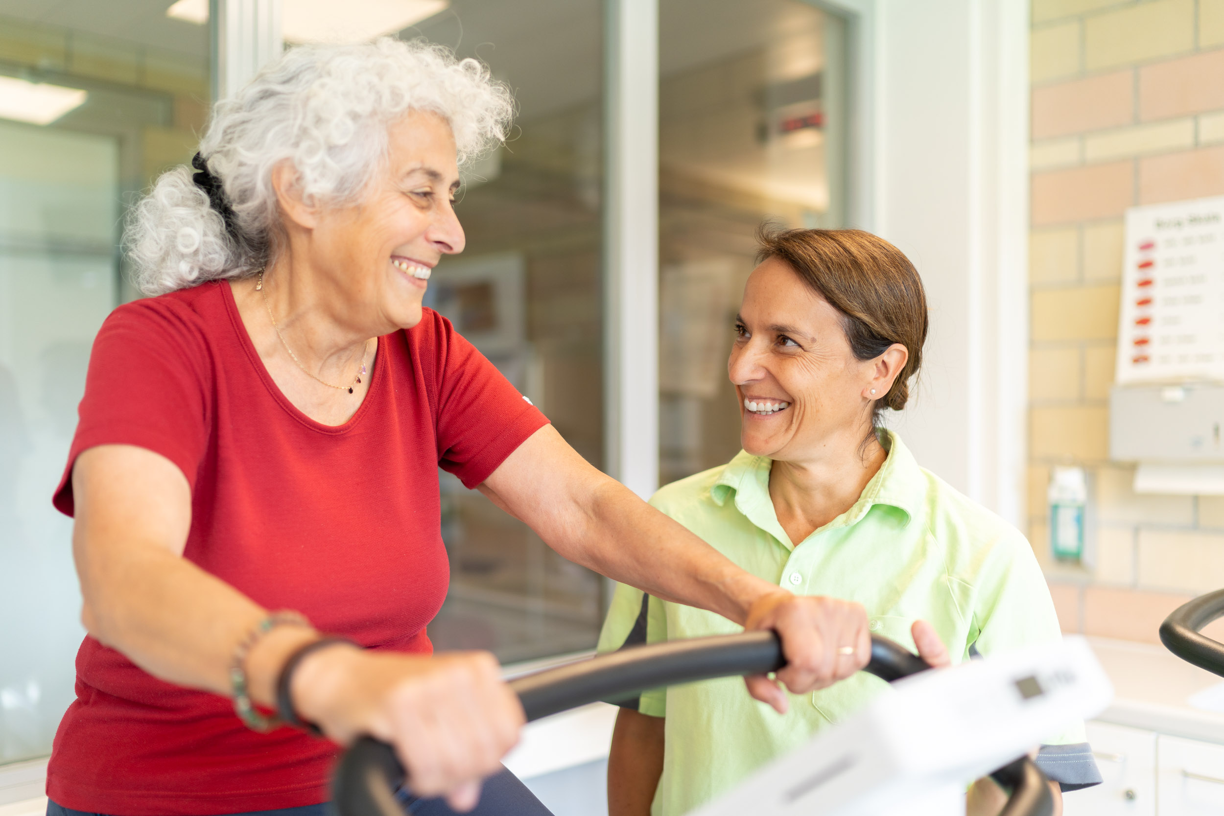 Patientin auf Ergometer, begleitet von Therapeutin