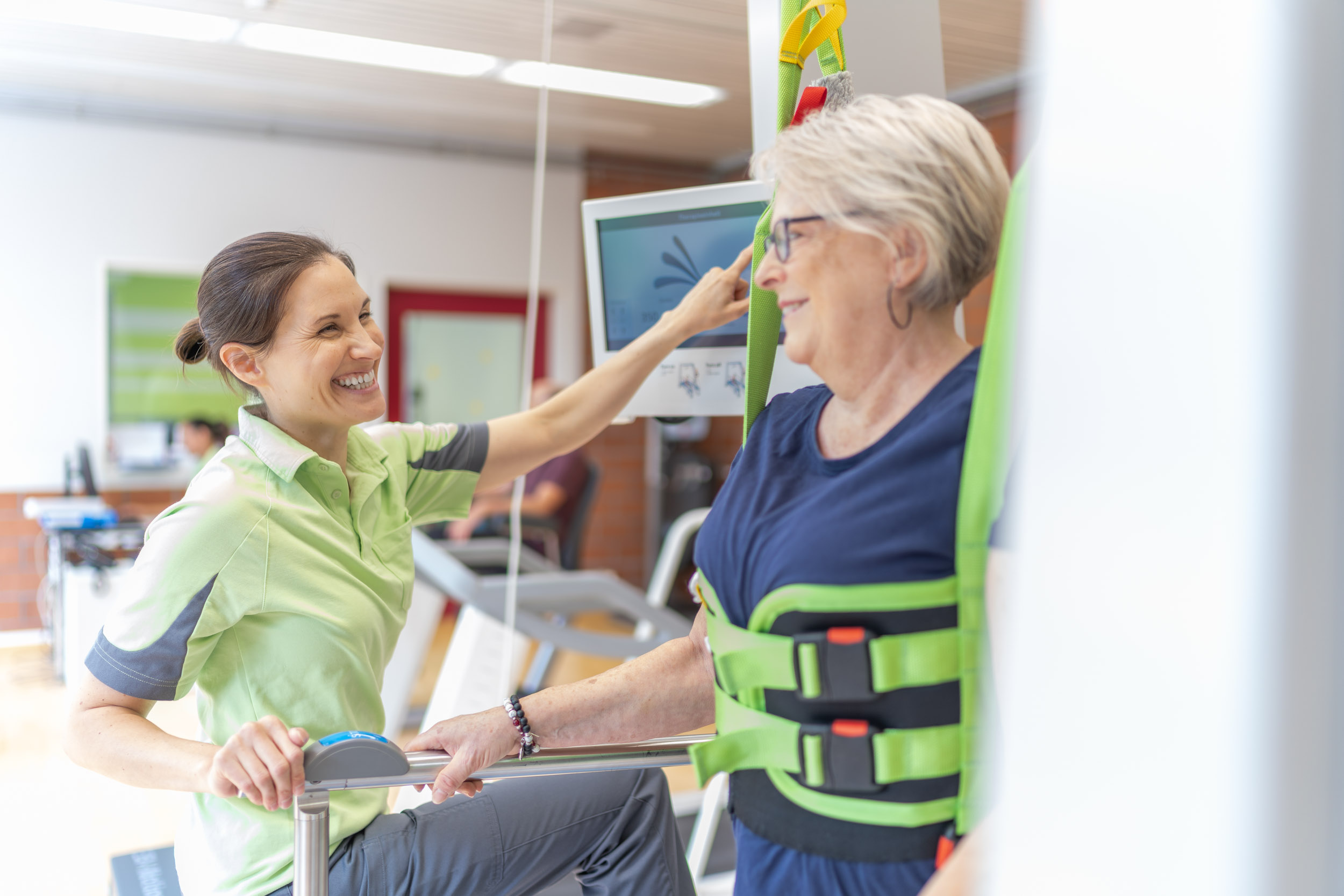 Therapeutin mit Patientin an einem Trainingsgerät