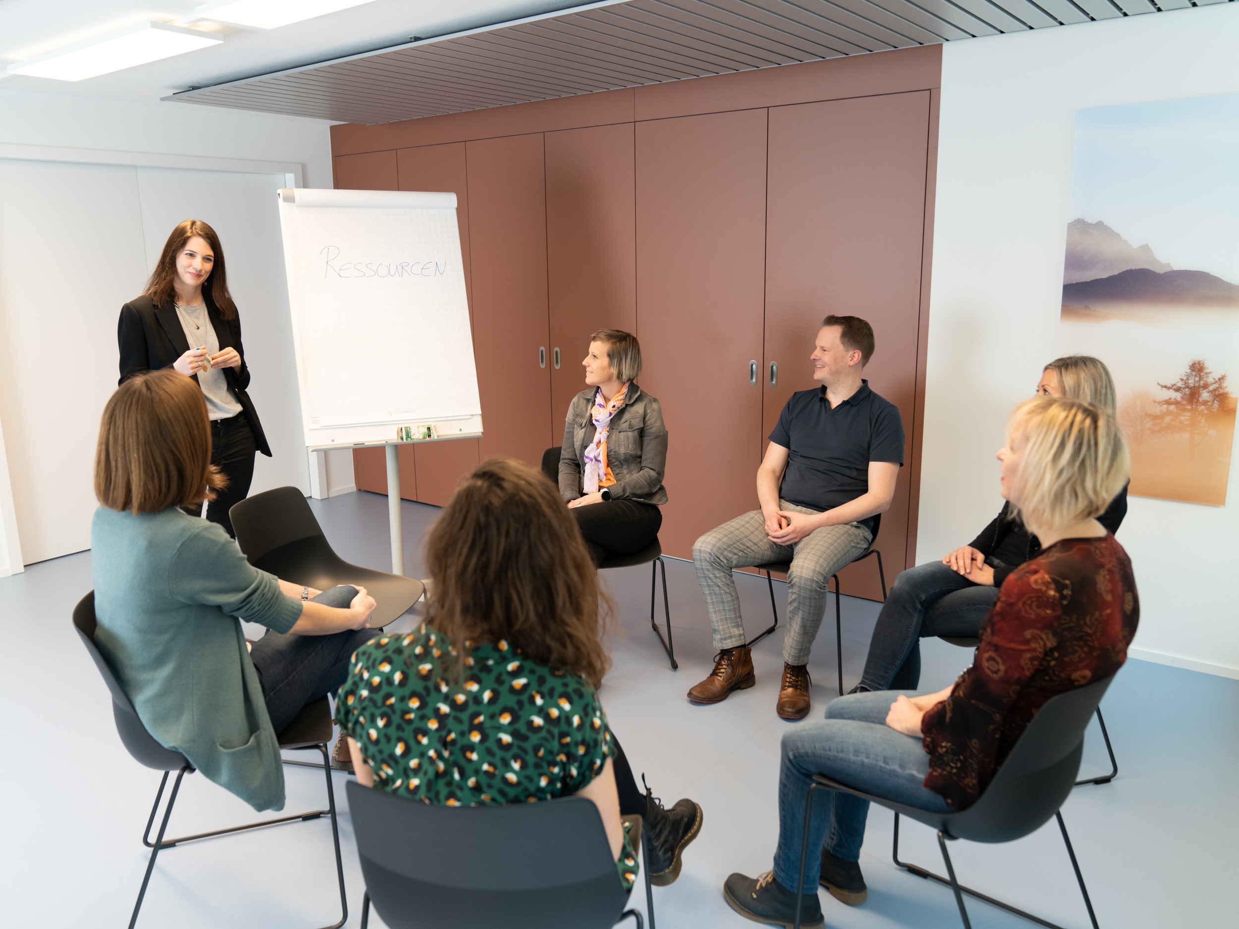 Gruppentherapie. Patienten sitzen im Kreis, Psychologin am Whiteboard