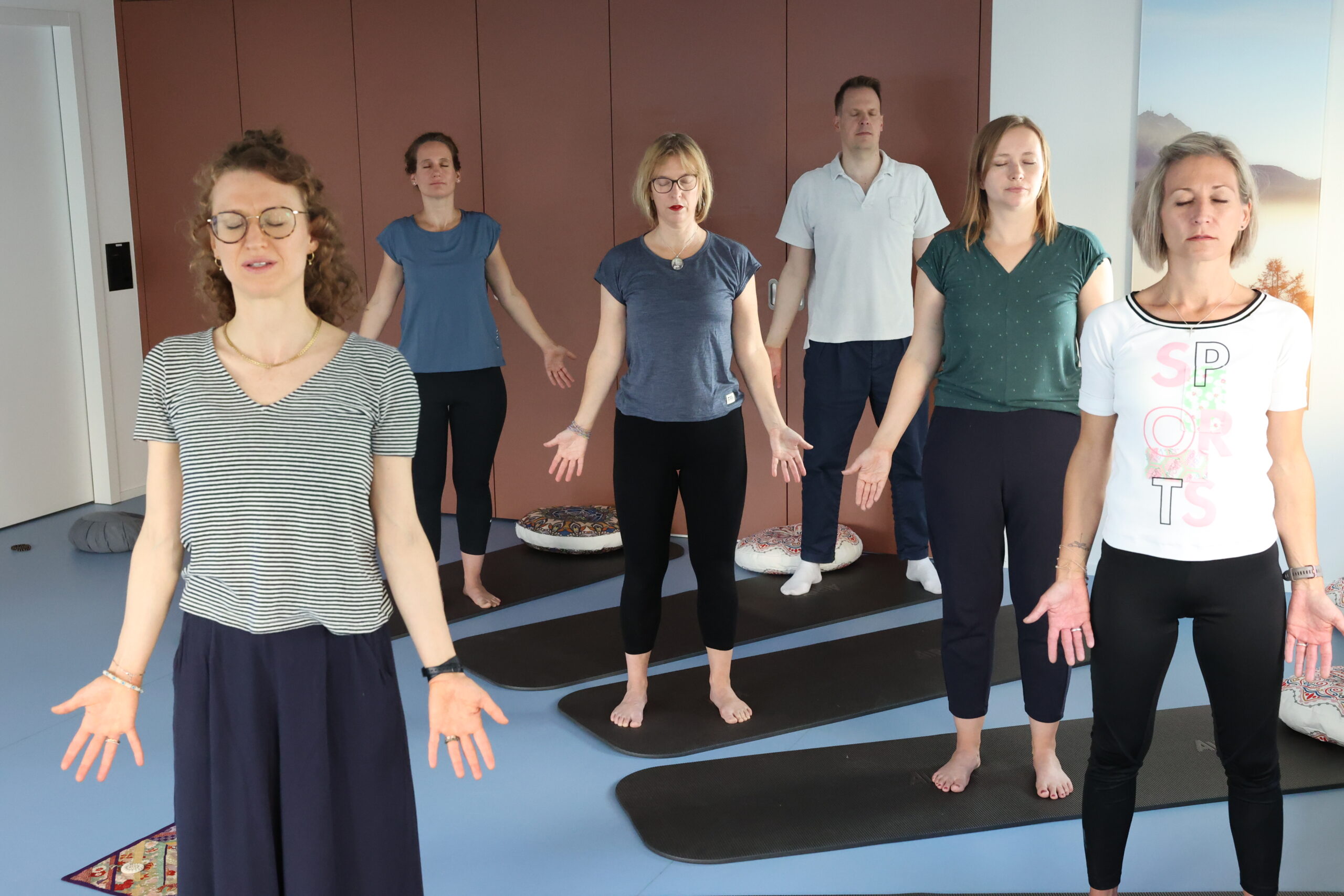 Mehrere Personen stehend beim Yoga