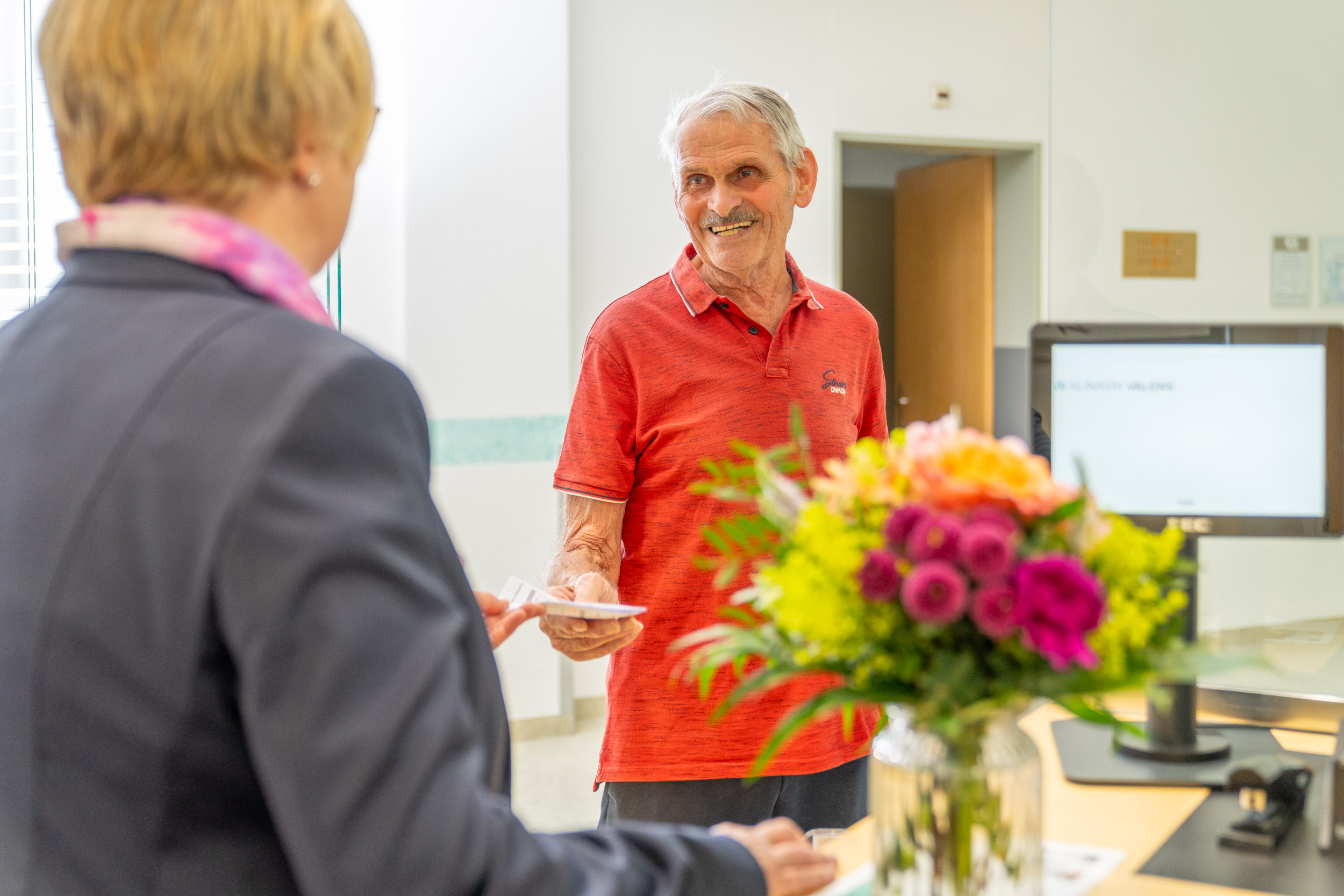 Älterer Herr bekommt eine Broschüre an der Reception