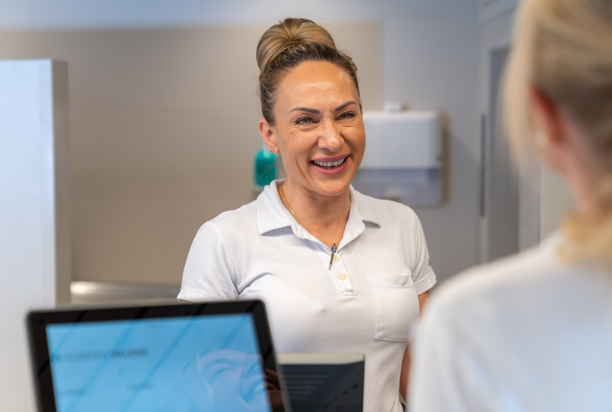 Servicemitarbeiterin lächelt Patientin an