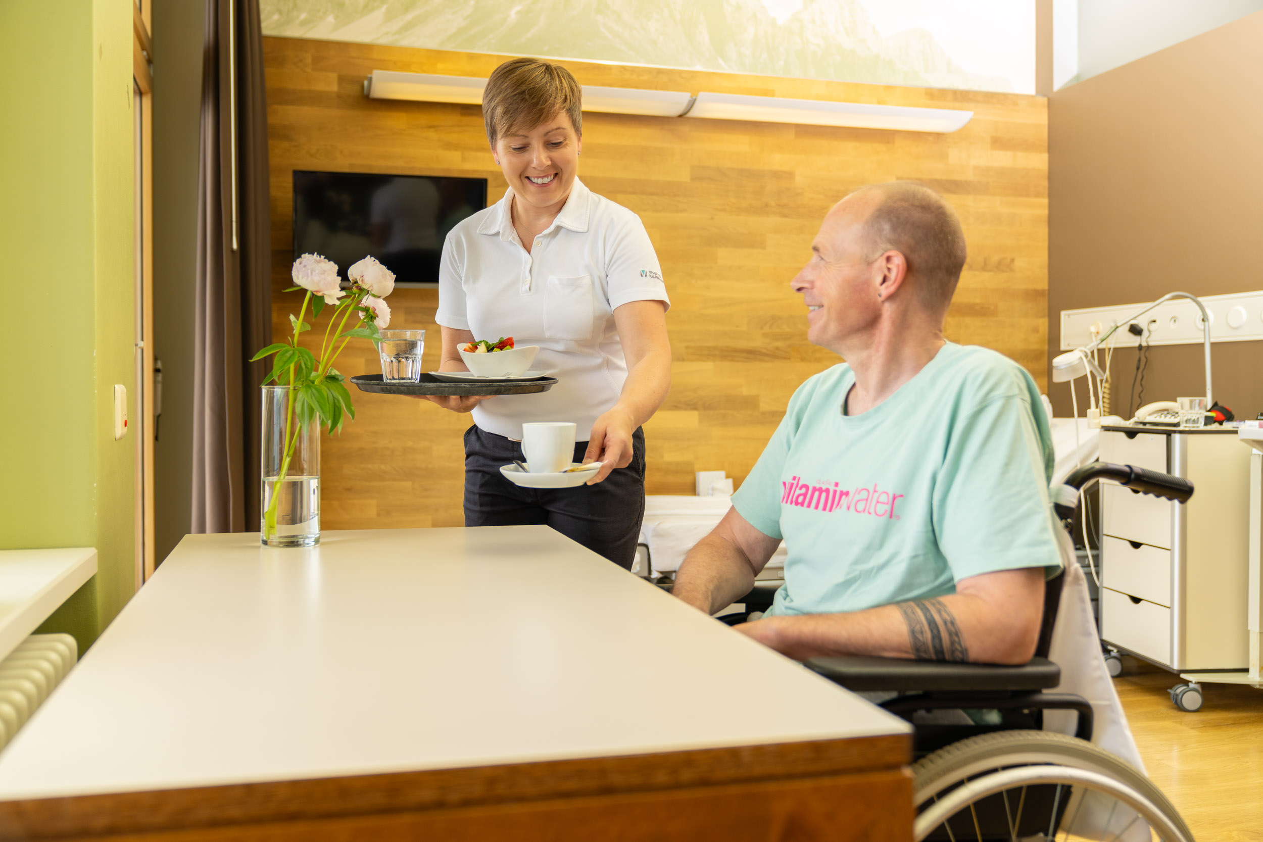 Servicemitarbeiterin bedient Patient im Zimmer