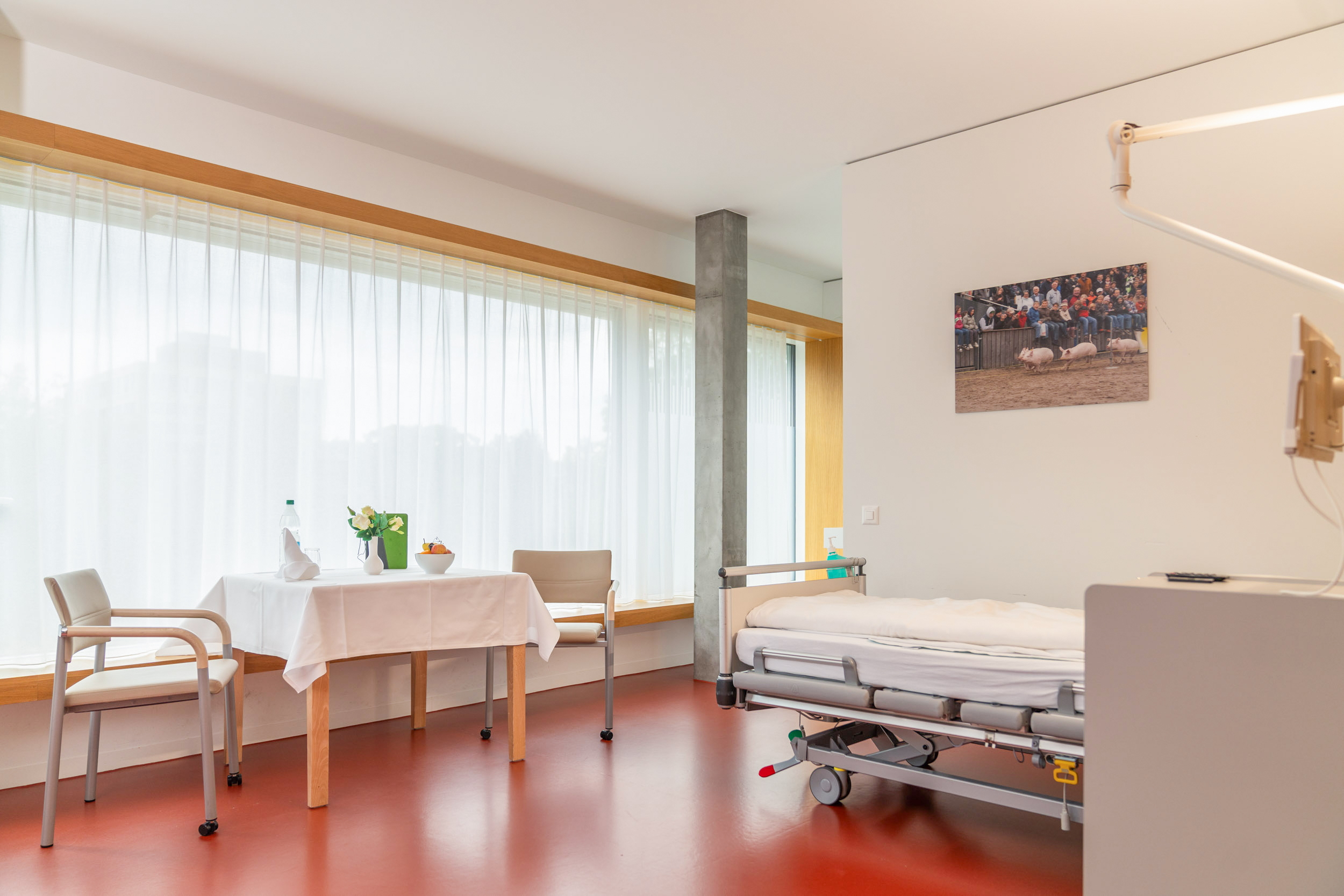 Patientenzimmer mit Bett, Tisch und Stühlen