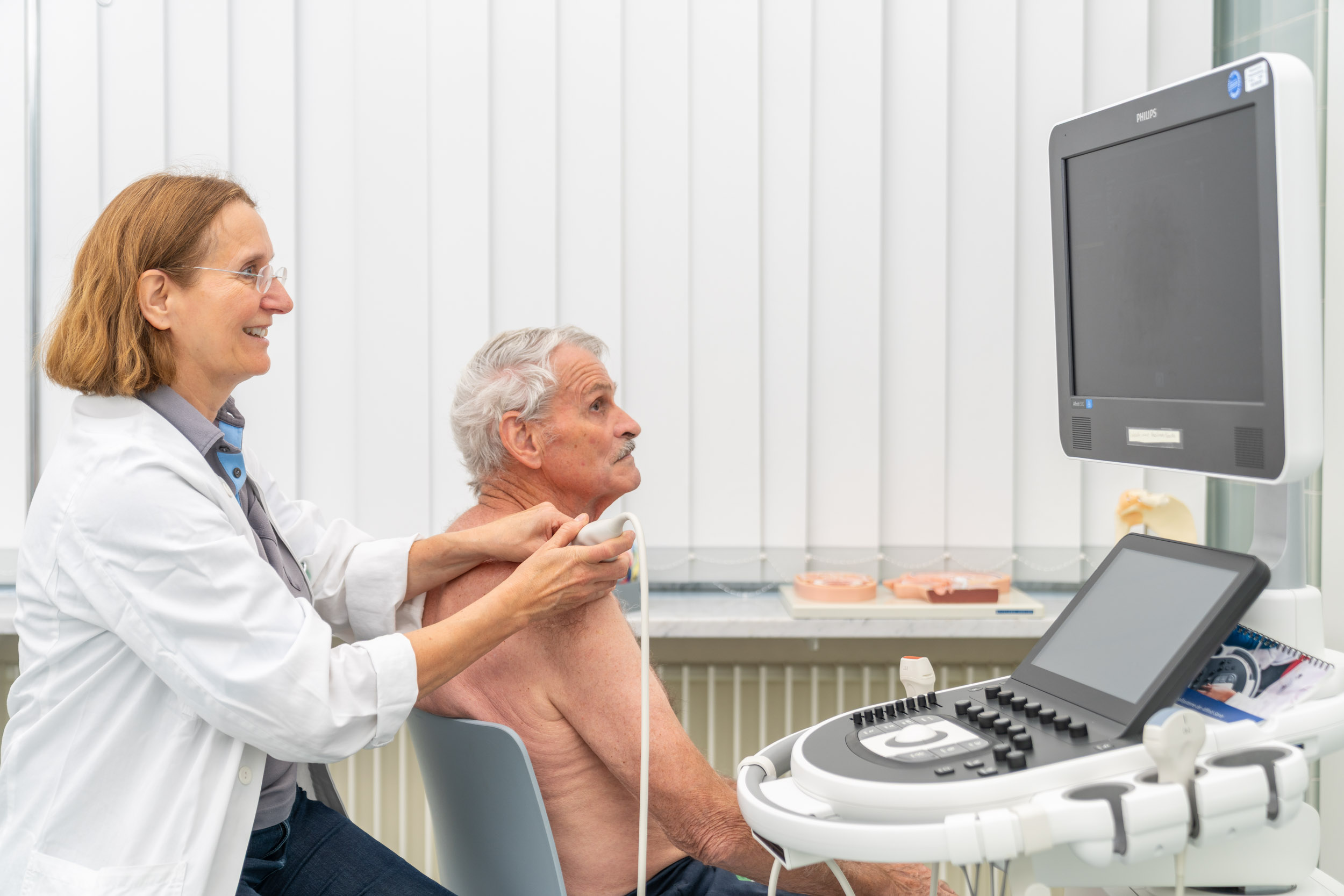 Ärztin untersucht Patient mit Ultraschall an der Schulter