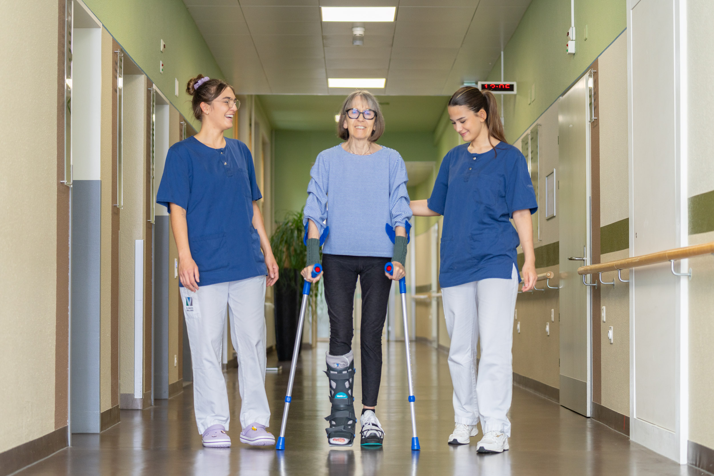 Zwei Pflegefachfrauen begleiten Patientin beim Gehen