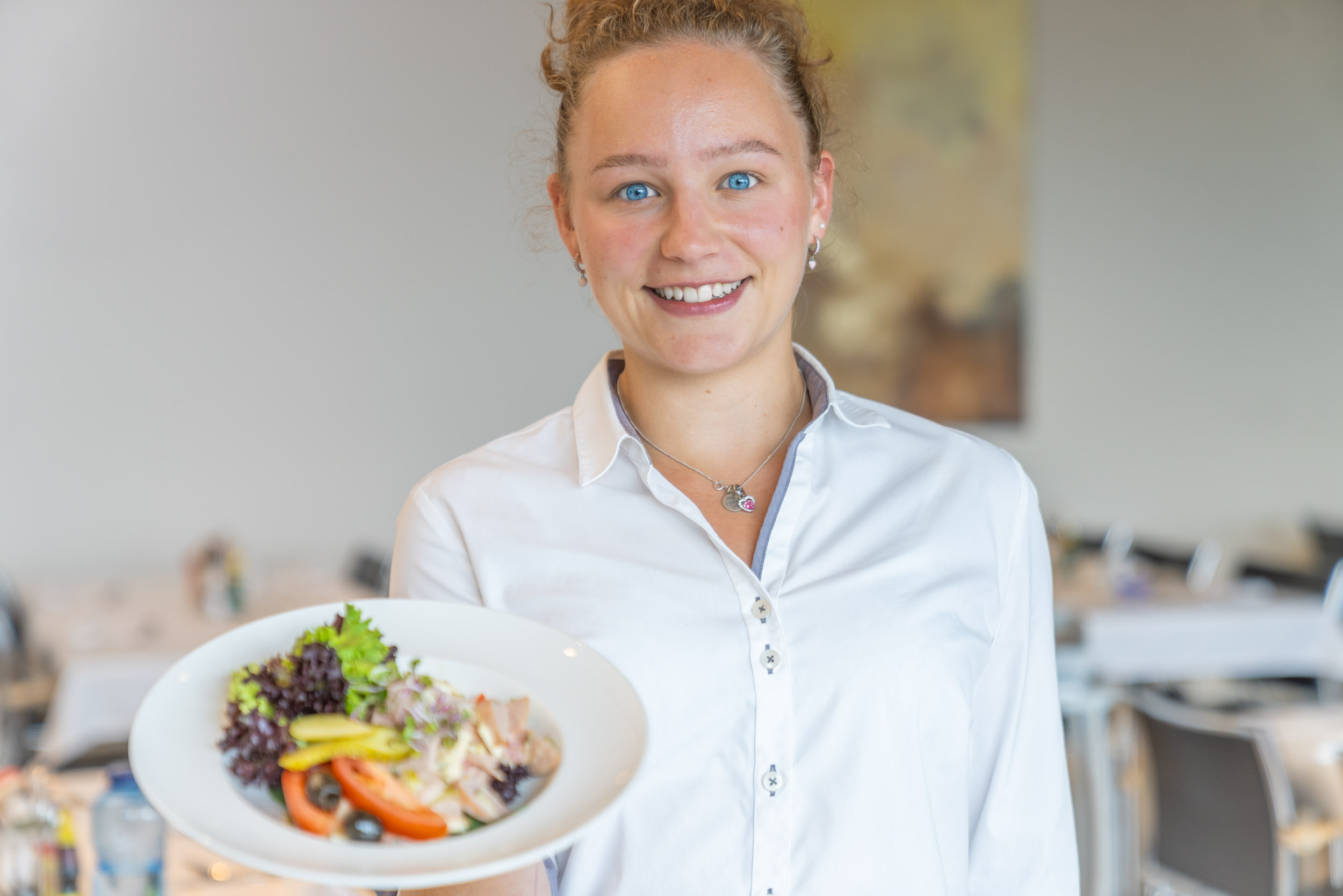 Junge Servicemitarbeiterin präsentiert Teller