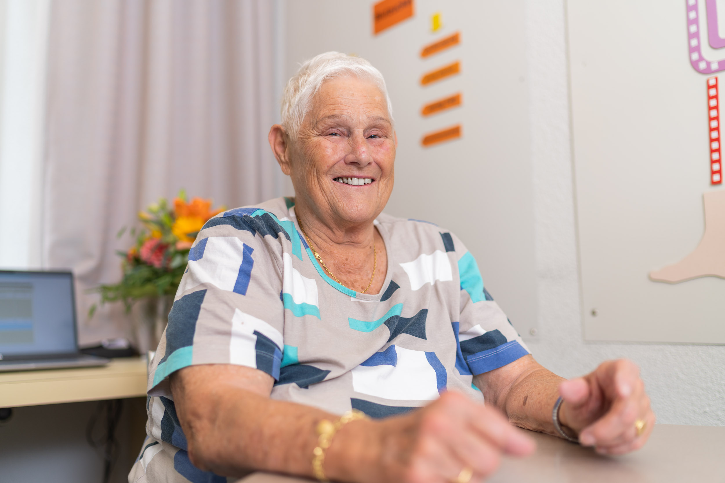 Ältere Patientin lächelnd am Tisch