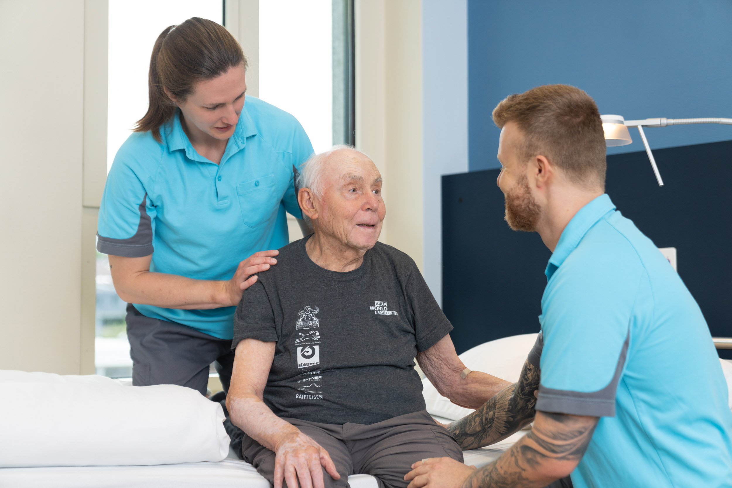 Älterer Patient sitzend, mit Pflegefachpersonen