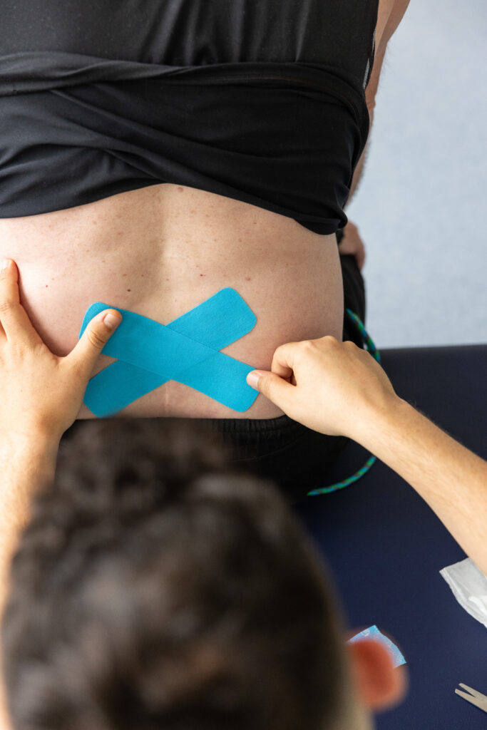 Therapeut bringt Tapes auf dem Rücken von Patient an