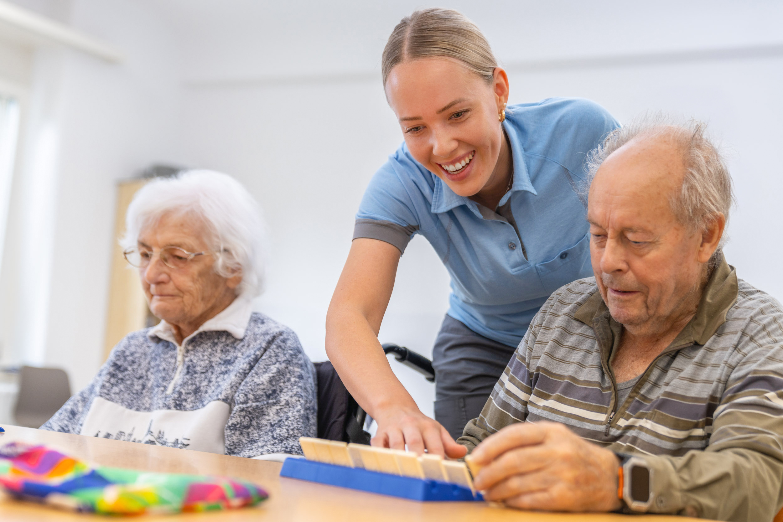 Ergotherapeutin mit zwei älteren Patienten am Tisch